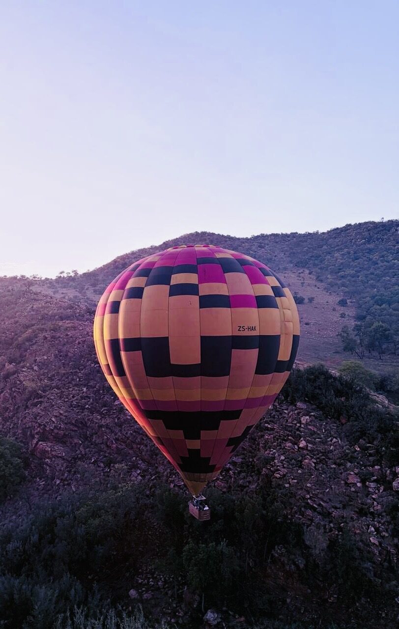A single balloon rising over the mountain ridge at first light