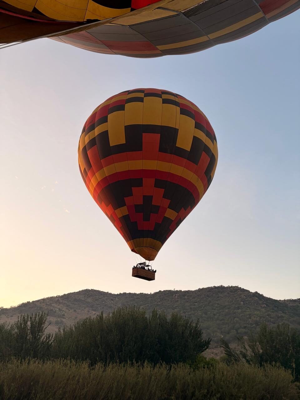 A single balloon drifting over the mountains at sunrise