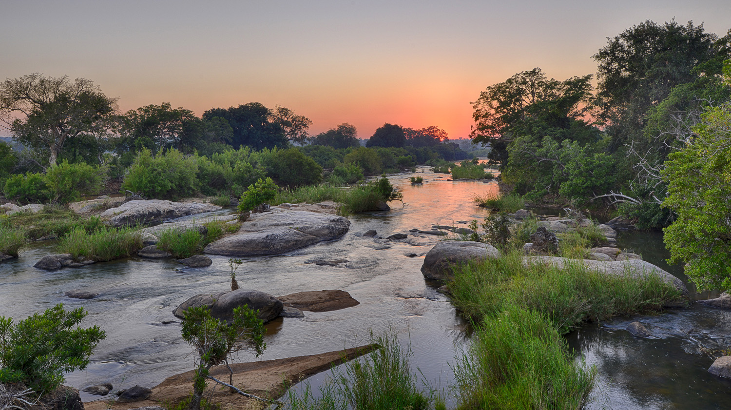 The Sabie River at sunset near Lower Sabie camp — hippos grunt in the water while the sky turns amber and purple
