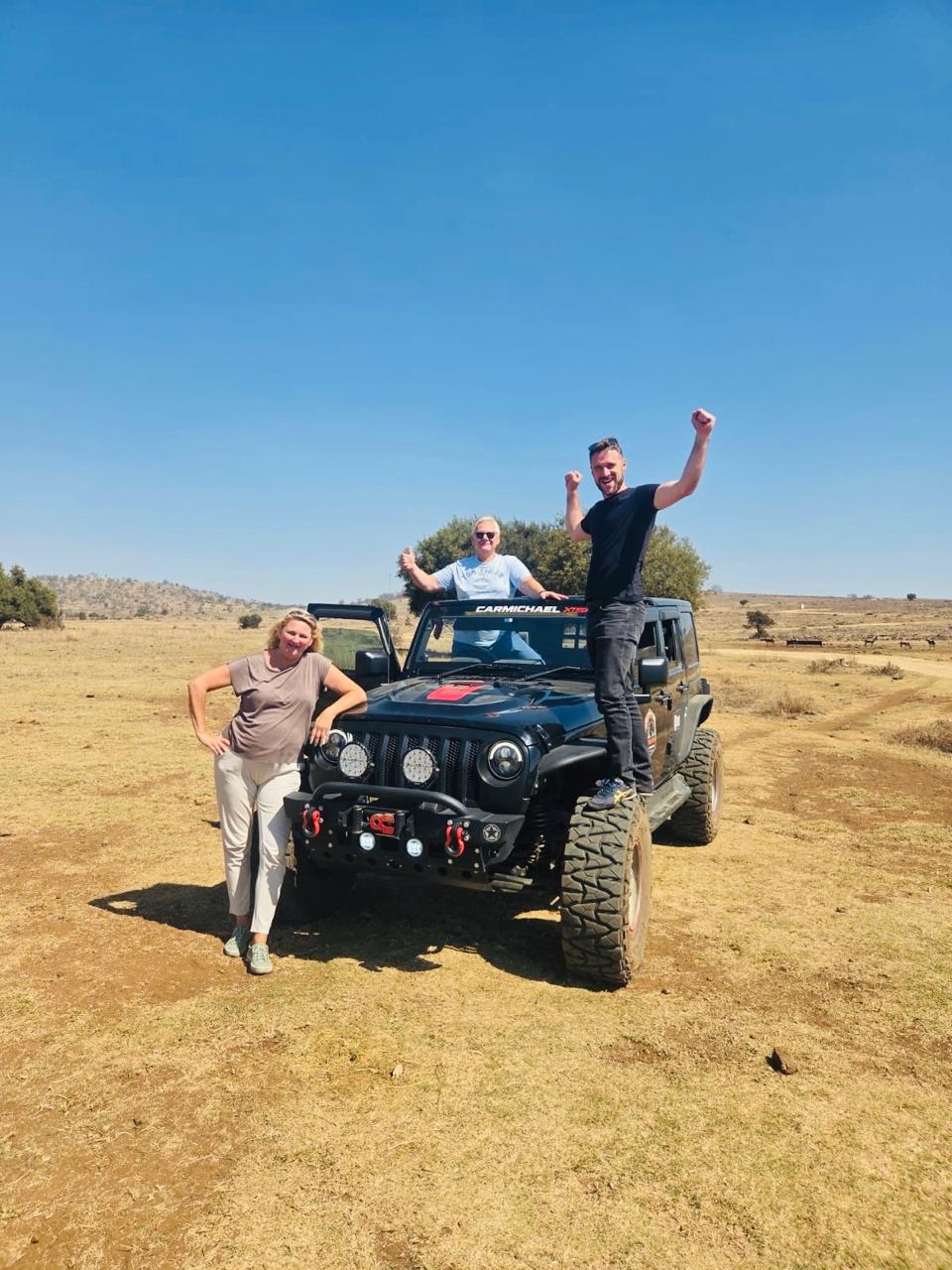 Happy guests posing with the rugged safari jeep at the Lion and Safari Park during the predator experience