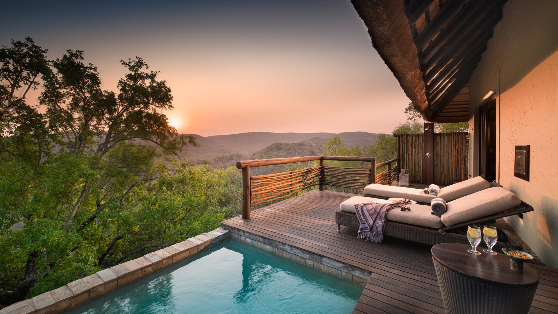 A luxury safari suite deck with private plunge pool overlooking the African bush at sunset