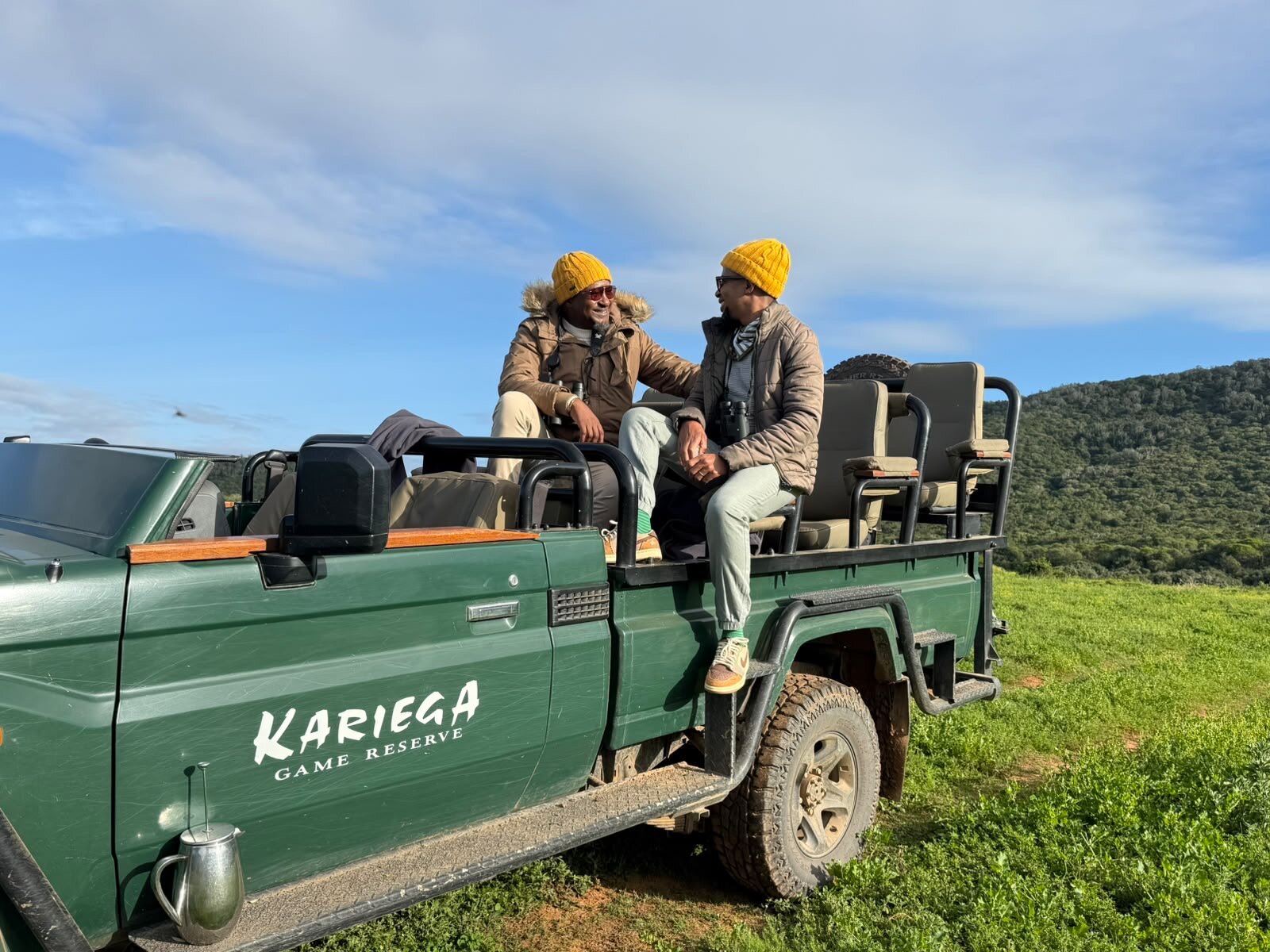 Thabo and Katlego laughing together and holding hands on the safari vehicle